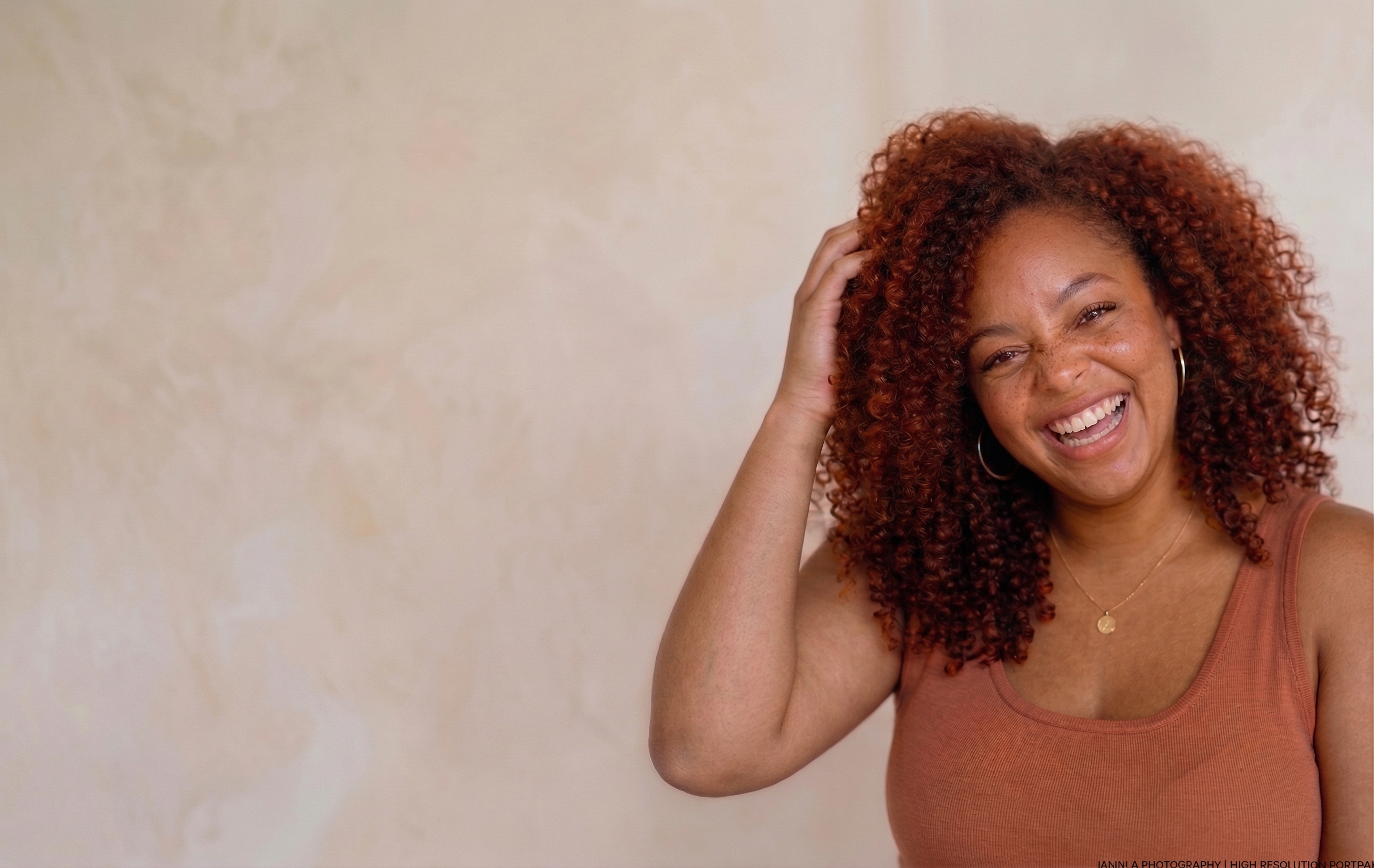 Beautiful Black woman laughing joyfully with curly hair and terracotta top